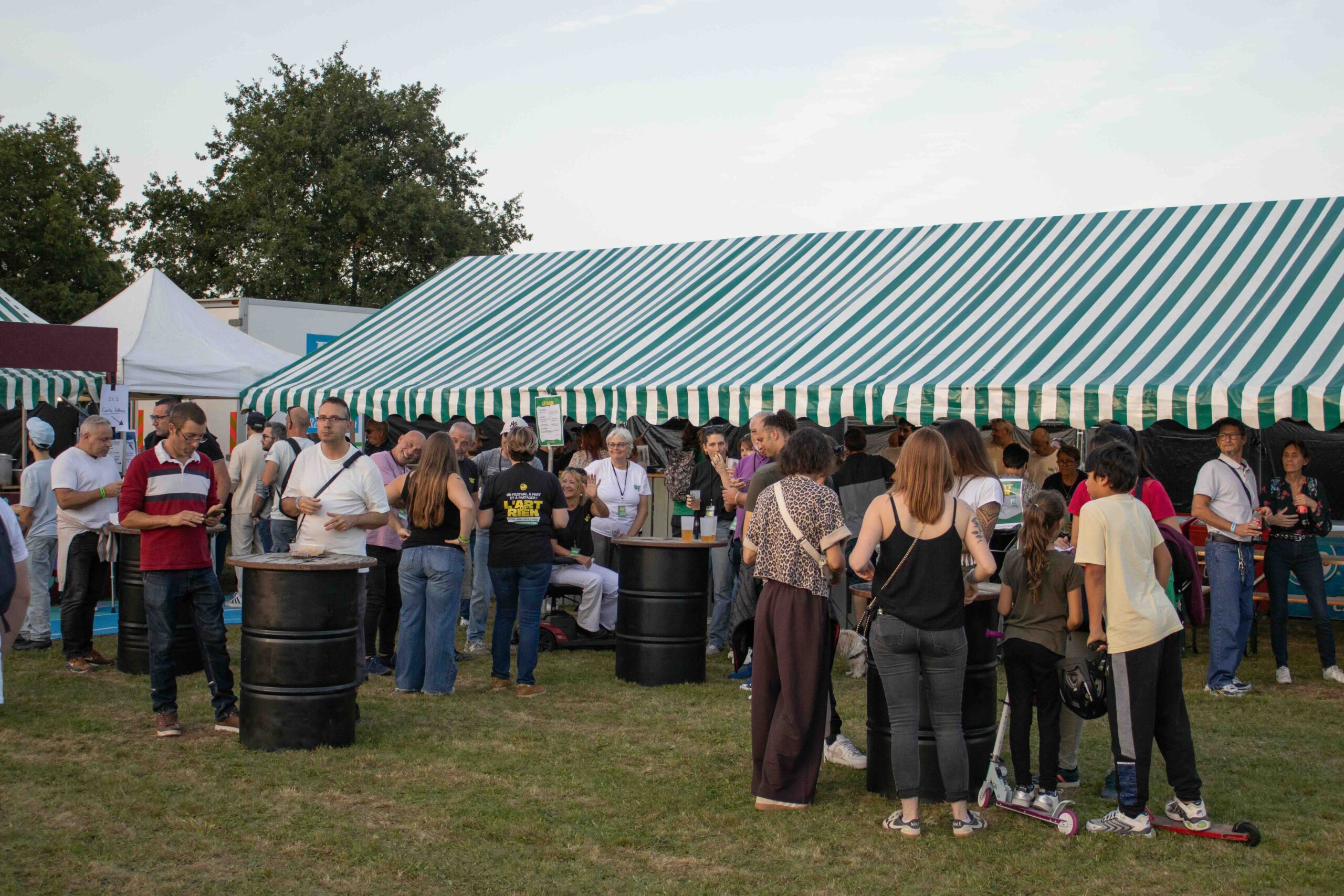 Festivaliers en fin de journée entre les tentes du site de L'Art de Rien, aller seul a un concert ou en festival le temps d'une soirée